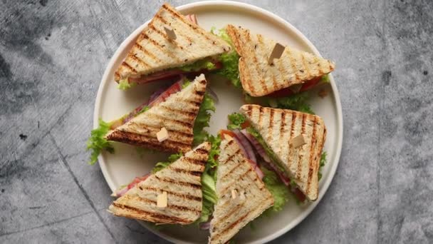 Sandwich club savoureux et frais servi sur une assiette en céramique blanche — Video