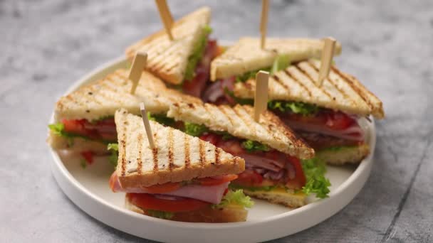 Sandwich club savoureux et frais servi sur une assiette en céramique blanche — Video