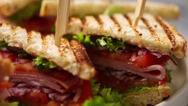 Close-up sobre apetitosos sanduíches de clube grelhados frescos e saudáveis com presunto e queijo — Vídeo de Stock