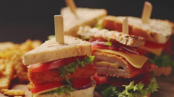 Σάντουιτς με κοτόπουλο και τυρί που σερβίρονται σε ξύλινη σανίδα με τηγανητές πατάτες — Αρχείο Βίντεο
