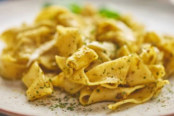 Close-up van vers gekookte tagliatelle pasta met groene pesto en kruiden — Stockfoto