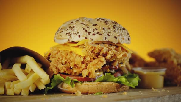 Hambúrguer de frango crocante com queijo cheddar, alface, tomate, cebola. Servido com batatas fritas e mostarda — Vídeo de Stock