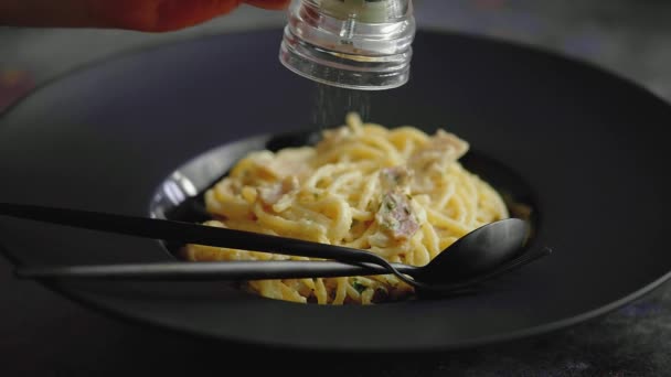 Повільне відео руху пластини з спагетті карбонара посипається свіжим перцем — стокове відео