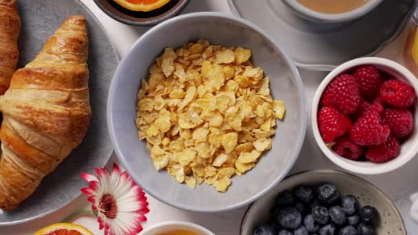 Смачний сніданок з кукурудзяними пластівцями кава, круасан, молоко та різні види ягід — стокове відео