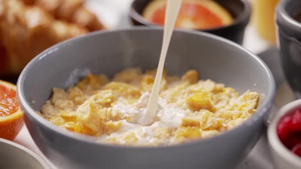 Milk pouring into bowl full of corn flakes with splashing. Healthy breakfast concept — Stock Video