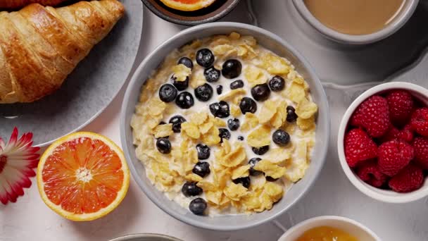Conceito de café da manhã saudável com flocos de milho e bagas frescas na mesa branca — Vídeo de Stock