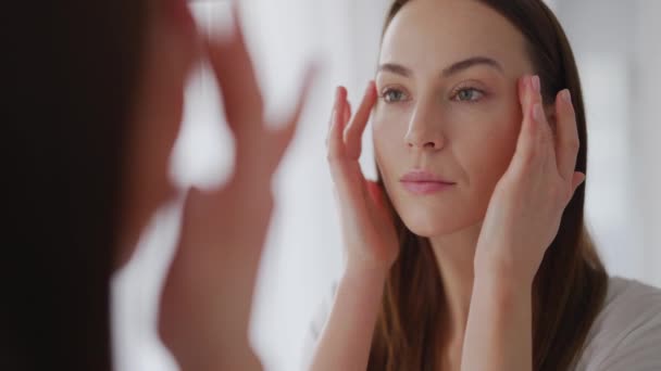 O femeie examinează pielea perfectă lângă oglindă — Videoclip de stoc