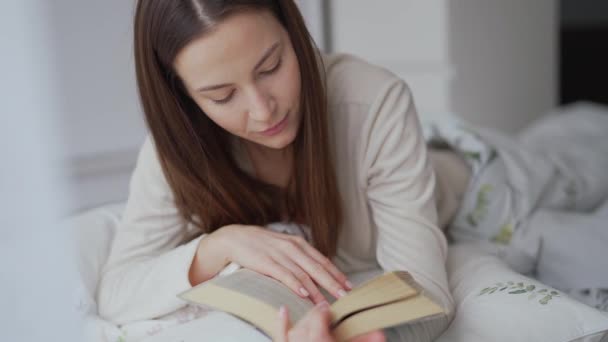 Mujer disfrutando leyendo en la cama — Vídeos de Stock