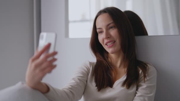 Веселая женщина делает видеозвонок возле зеркала — стоковое видео