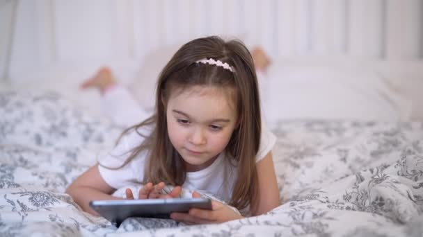 Veselý dívka pomocí tablet na posteli — Stock video
