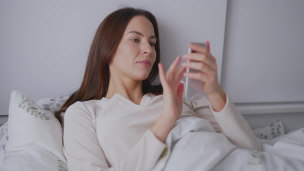 Vrouw met smartphone op bed — Stockvideo