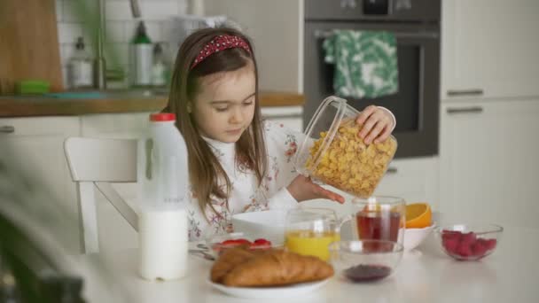 Dziewczyna wylewa płatki do miski podczas śniadania — Wideo stockowe
