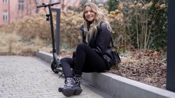 Mulher feliz com scooter elétrico descansando no parque de outono — Vídeo de Stock