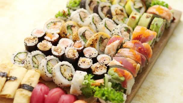 Vista acima de vários sushi e rolos colocados em tábua de madeira. Festa de comida japonesa — Vídeo de Stock