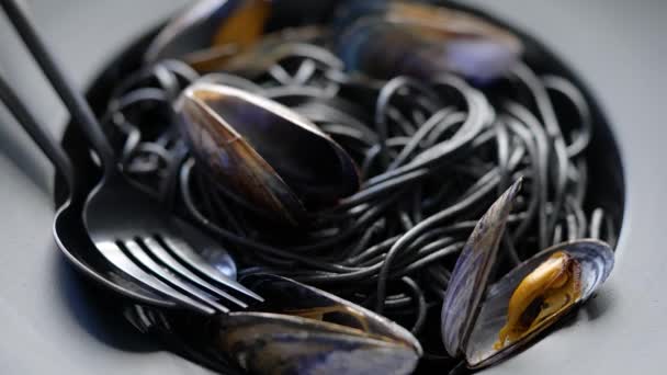 Primer plano de deliciosa pasta de espagueti negro servido con mejillones en plato oscuro — Vídeos de Stock