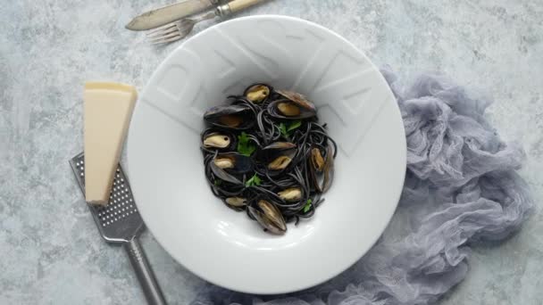Black seafood spaghetti pasta with mussels over stone background. Mediterranean delicious food — Stock Video