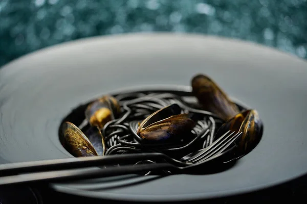 Морепродукти чорна паста спагетті з молюсками, поданими на чорній тарілці на темному камені — стокове фото