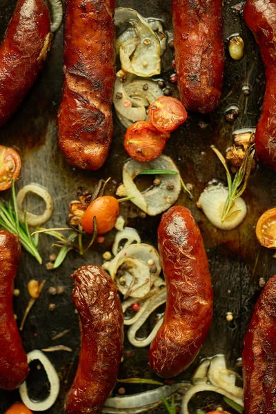 Lekkere gegrilde zelfgemaakte rozemarijn worsten geplaatst op ijzeren bakplaat over rustieke donkere stenen tafel — Stockfoto