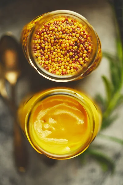 Two kinds of mustard. Frensh with whole seeds and honey served in glass jars