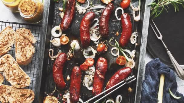 Top view on delicious grilled sausages served with onion, tomatoes, garlic, bread and herbs — Stock Video