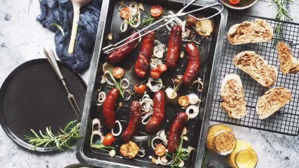 Top view a finom grillezett kolbászok felszolgált hagyma, paradicsom, fokhagyma, kenyér és gyógynövények — Stock videók