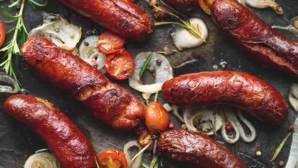 Blick auf köstliche Grillwürste mit Zwiebeln, Tomaten, Knoblauch, Brot und Kräutern — Stockvideo