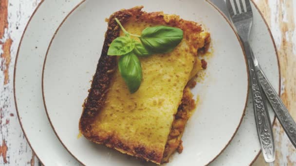 Zelfgemaakte smakelijke vleeslasagne met verse basilicum en parmezaanse kaas in een bord op houten ondergrond — Stockvideo