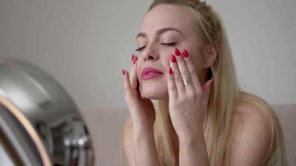 Mujer joven untando crema en la cara — Vídeos de Stock
