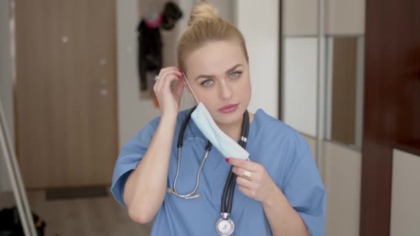 Женщина-врач надевает маску дома — стоковое видео