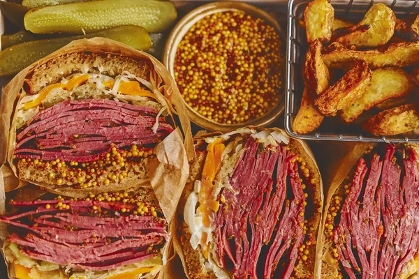 Enorme broodjes met pastrami rundvlees in houten doos. Geserveerd met gebakken aardappelen, augurken — Stockfoto