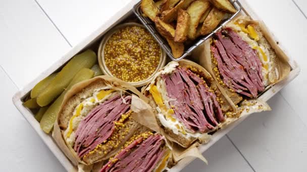 Enorme broodjes met pastrami rundvlees in houten doos. Geserveerd met gebakken aardappelen, augurken — Stockvideo