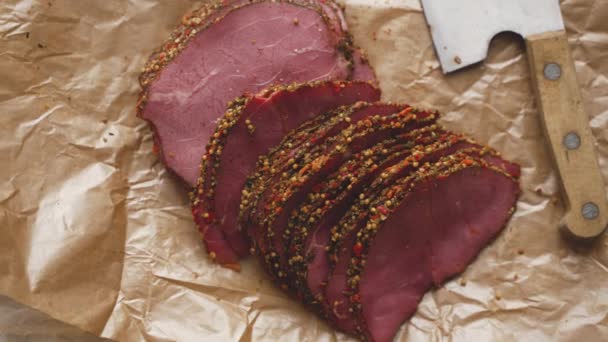 Νόστιμες φέτες πεπιεσμένου βοείου κρέατος παστουρμά σε χαρτί με κόκκους έγχρωμου πιπεριού — Αρχείο Βίντεο