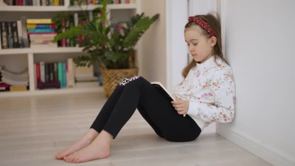Předškolní dívka čtení knihy v domácí knihovně — Stock video