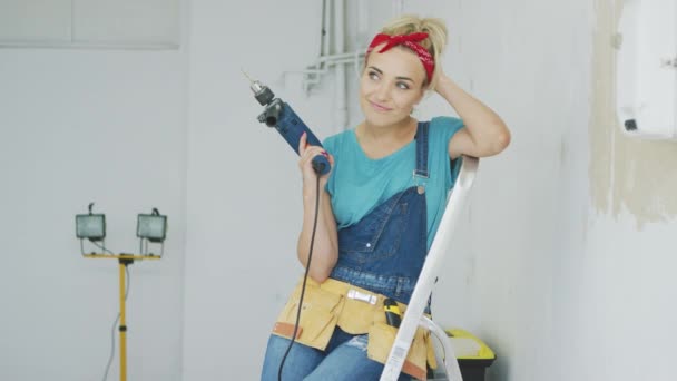 Happy woman with drill sitting on stepladder — Stock Video