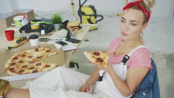 Женщина-плотник ест пиццу на рабочем месте — стоковое видео