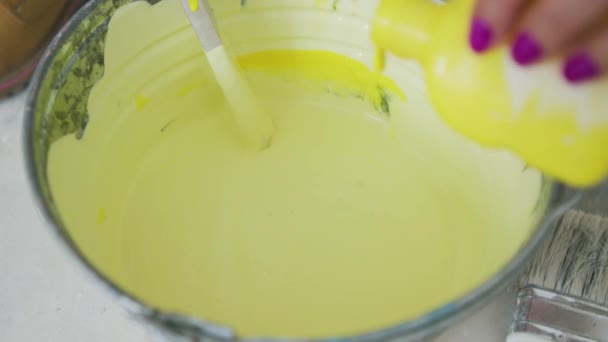 Hand mixing yellow wall paint in bucket — Stock Video