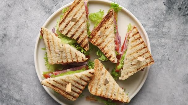 Вкусный и свежий клубный сэндвич подается на белой керамической тарелке — стоковое видео