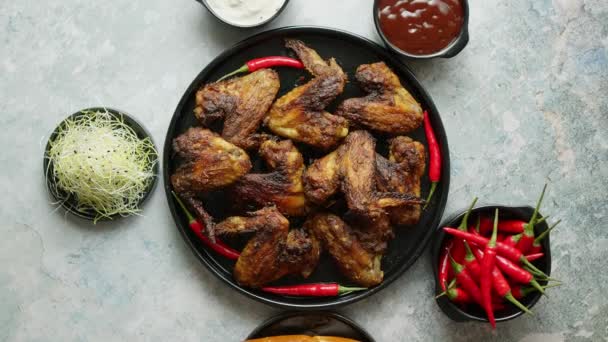 Gegrillte Chicken Wings mit Chilipfeffer auf einem rustikalen Teller serviert mit verschiedenen Dips und Brot — Stockvideo