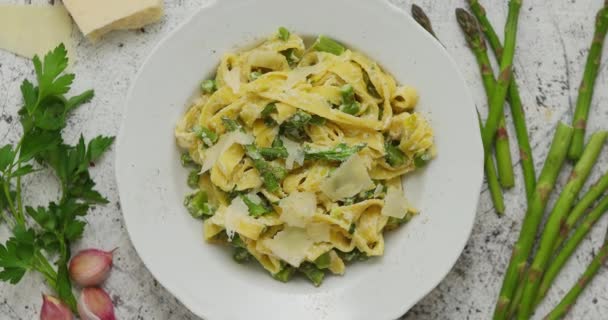 Hausgemachte Tagliatelle-Pasta mit cremiger Ricottasauce und Spargel auf weißem Keramikteller — Stockvideo