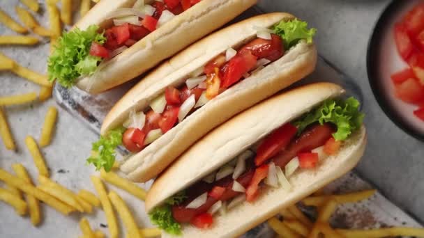 Három ízletes hot dog választéka, fa vágódeszkára helyezve — Stock videók