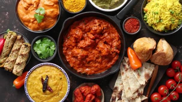 Különböző indiai ételek az asztalon. Fűszeres csirke Tikka Masala vasserpenyőben — Stock videók