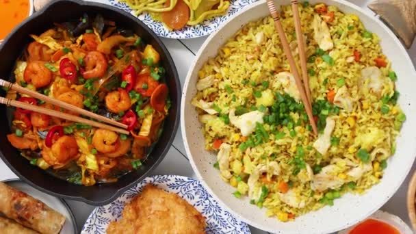 Asiatisk mat serverad. Plattor, stekpannor och skålar fulla med nudlar kyckling rör om yngel och grönsaker — Stockvideo