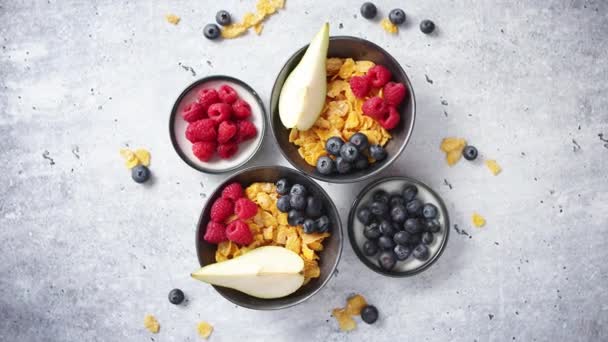 Golden cornflakes with fresh fruits of raspberries, blueberries and pear in ceramic bowl — Stock Video