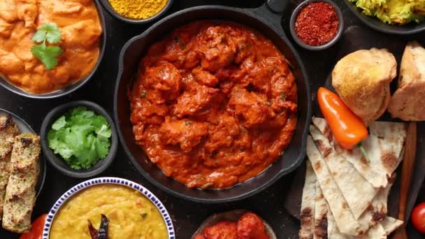 Verschiedene indische Gerichte auf einem Tisch. Würzige Huhn Tikka Masala in eiserner Pfanne — Stockvideo