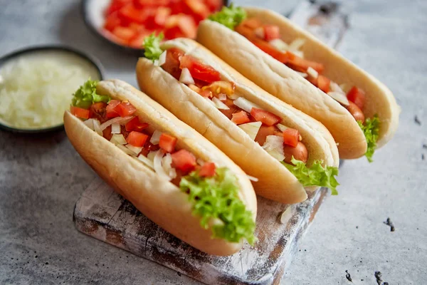 Berbagai macam tiga tasety hot dog, ditempatkan di papan potong kayu — Stok Foto