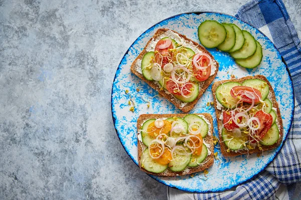 Prato com torradas com pepino, tomate e feta desintegrado e brotos de rabanete — Fotografia de Stock