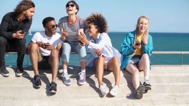 Молодые люди с мобильными телефонами на берегу моря — стоковое видео