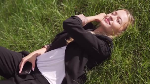İş kadını parkta çimlerde yatıyor. — Stok video