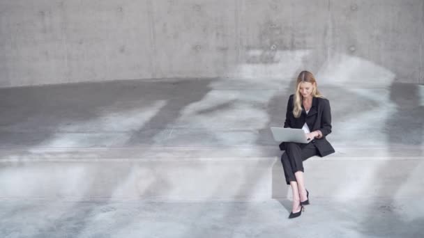 Female entrepreneur using laptop outside concrete building — Stock Video