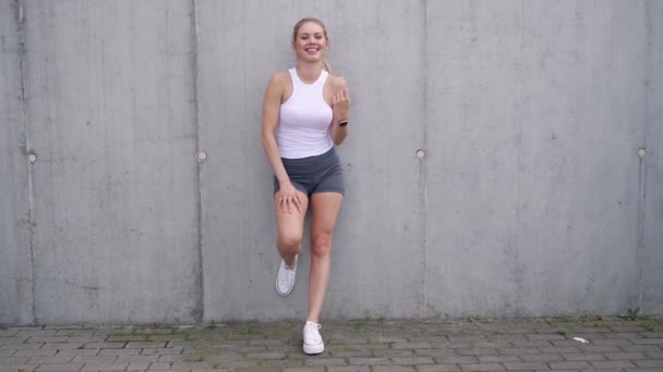 Optimistische vrouwelijke atleet neemt pauze in de buurt muur — Stockvideo